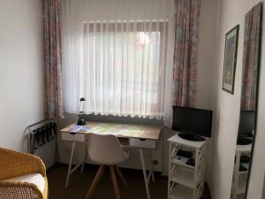 a desk in a room with a window and a television at Hotel Del Sol in Bad Wildungen