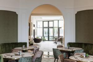 een restaurant met tafels en stoelen en een groot raam bij C-Hotels Continental in De Panne