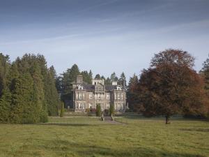 a large house in a field with a tree at Clonalis House - Guesthouse in Castlerea