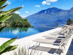 a row of lounge chairs next to a body of water at Stella D'Oro - Hotel & Apartments in Tremosine Sul Garda