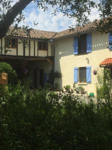 a white house with blue windows and bushes at Michouat Chambre D'Hotes in Vidou