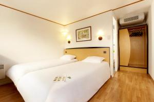 duas camas num quarto com lençóis brancos em Campanile Nevers Nord - Varennes-Vauzelles em Varennes Vauzelles