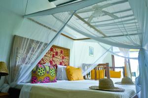 a bedroom with a white bed with a canopy at Spice Island Hotel & Resort in Jambiani