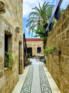 a courtyard with a stone wall and a table and chairs at Hotel Ellique in Rhodes Town