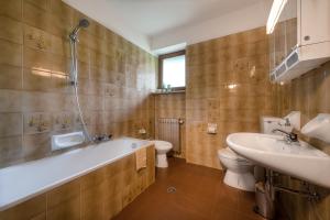 a bathroom with a tub and a toilet and a sink at Ringlerhof in Braies