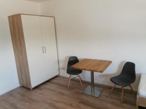 Zimmer mit einem Tisch, 2 Stühlen und einem Schrank in der Unterkunft Am Mühlbach0 in Bodenheim