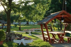 un parque con banco de madera y cenador en Szegedi Partfürdő Kemping és Apartman en Szeged