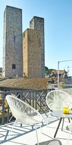 due sedie bianche e un tavolo e un edificio di S.M. VICOLO DELL'ORO a San Gimignano