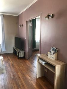 ein Wohnzimmer mit einem TV und Holzböden in der Unterkunft appartement de charme en plein coeur du centre ville de Compiègne arriver entre 14h et 18h maximum in Compiègne