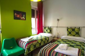 een groene kamer met 2 bedden en een stoel bij Pensión Blanca B&B in León