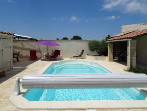 una piscina en un patio con sombrilla en Studio l'Obrador 25 m2, vue jardin & terrasse + accès piscine, en Rieux-Minervois