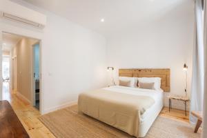ein weißes Schlafzimmer mit einem großen Bett und einem Flur in der Unterkunft Your Lisbon Home Bairro Alto in Lissabon