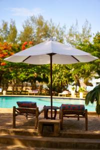 a white umbrella and two chairs next to a pool at Spice Island Hotel & Resort in Jambiani