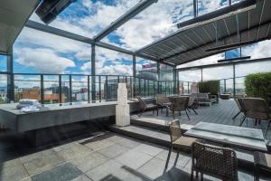 a rooftop patio with chairs and tables and windows at BOG Hotel in Bogotá