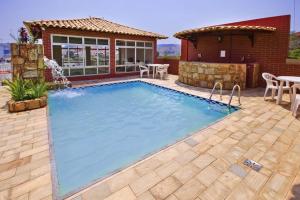 a swimming pool with a patio and a house at Ubaense Plaza Hotel in Ubá