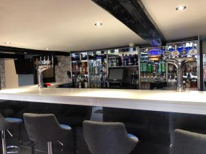 a bar with bar stools and bottles of alcohol at The Old Black Horse Inn in Oxford
