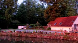 a house with a red roof next to a body of water at River Cottage in Balledent