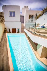 a house with a swimming pool in front of a house at Pjazza Suites Boutique Hotel by CX Collection in Siġġiewi