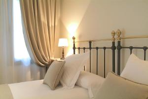 a bed with white pillows and a lamp next to a window at Le Petit Boutique Hotel in Santander