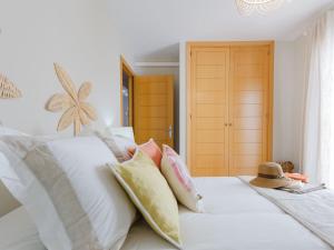 a white bed with pillows and a hat on it at La Marina II, luminoso apartamento junto a la playa in Torre de Benagalbón