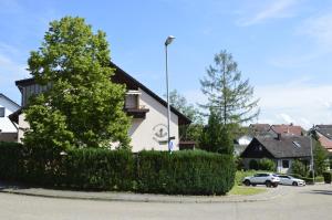 a white house with a hedge in front of a street at Gästehaus Fäßle in Weinstadt