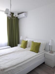 ゴールデン・サンズにあるOcean BAYの白いベッド(緑の枕付)が備わるベッドルームです。
