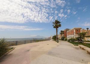 a walkway next to the ocean with buildings and a palm tree at Raimo House in Castellammare di Stabia