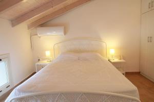 a white bed in a room with two tables at Xaradiotis House - A modern home away from home in Meganisi