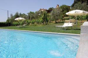 a swimming pool with two chairs and an umbrella at Podere Il Poggiolo in Rufina