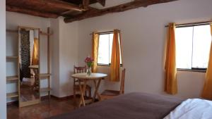 a bedroom with a bed and a table and two windows at Casa Inka B&B in Ollantaytambo