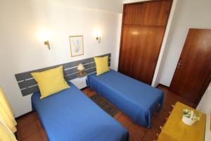 Duas camas num quarto com almofadas azuis e amarelas em ApartamentoSolPraia - BeloHorizonte em Portimão
