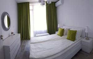 ゴールデン・サンズにあるOcean BAYのベッドルーム(緑のカーテン付きの白い大型ベッド1台付)