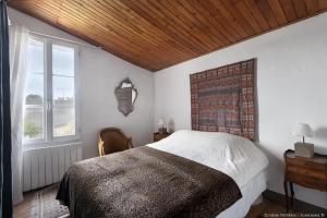 a bedroom with a large bed with a wooden ceiling at Le Clos du Vieux Porche in La Couarde-sur-Mer