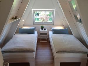 2 Betten in einem Dachzimmer mit Fenster in der Unterkunft Murmel 3 - Strandkorb, Wallbox, WLan, Kamin in Carolinensiel