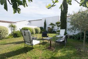 a group of chairs sitting next to a tree at Le Clos du Vieux Porche in La Couarde-sur-Mer