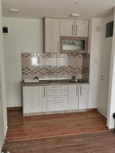 a kitchen with white cabinets and a wooden floor at Apartman MMS in Teslić