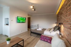 uma sala de estar com uma cama e uma parede de tijolos em Sea You Apartments- Okrzei em Sopot