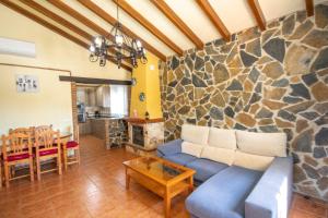 a living room with a blue couch and a stone wall at Cubo's Finca de la Rosa in Alhaurín el Grande