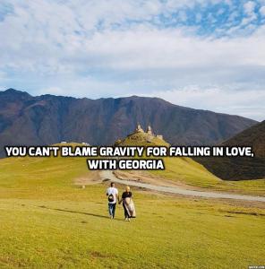 a couple of people walking in a field with the words you cant blame gravity for at Home of Bella & Tamo in Kazbegi