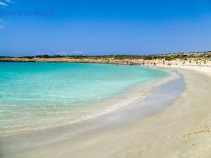 a beach with blue water and people on it at Amaryllis Hotel in Karpathos