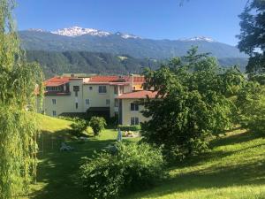 um grupo de edifícios numa colina com montanhas ao fundo em Austria Classic Hotel Heiligkreuz em Hall in Tirol