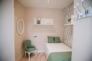 een kleine slaapkamer met een bed en een groene stoel bij La Atalaya, apartamento en Llanes in Llanes