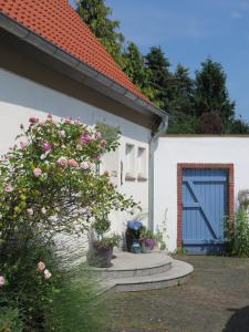 uma casa branca com uma porta azul e algumas flores em Marigold em Neumünster