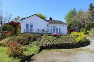 a white house on a hill with a garden at Drumgarry in Ardvasar