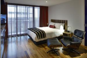 
a bedroom with a bed, chair and a window at Salamanca Wharf Hotel in Hobart
