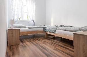 two beds in a white room with wooden floors at Apartament na Wyspie Piasek in Kłodzko