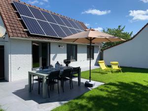 een tafel met stoelen en een parasol met zonnepanelen bij Duinendaele 232 met sauna bij Plopsaland en natuurreservaat in De Panne