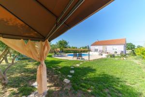 ein großer Sonnenschirm in einem Hof mit Pool in der Unterkunft Holiday house Roko in Gornji Zemunik