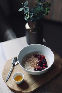 a bowl of oatmeal with berries and syrup on a table at Penzion U Kubesa - Adults only in Kroměříž +50 photos