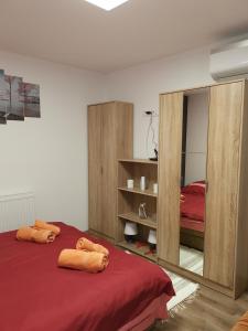 een slaapkamer met een bed met rode lakens en een spiegel bij Gál Apartmanház in Harkány